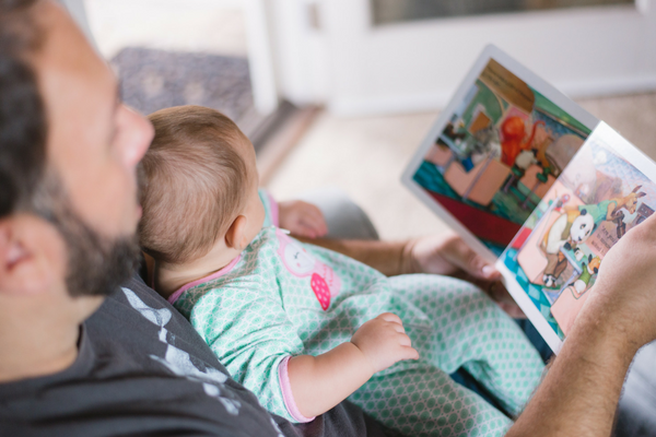 Caregiver reads to a baby | Sparkhouse Blog
