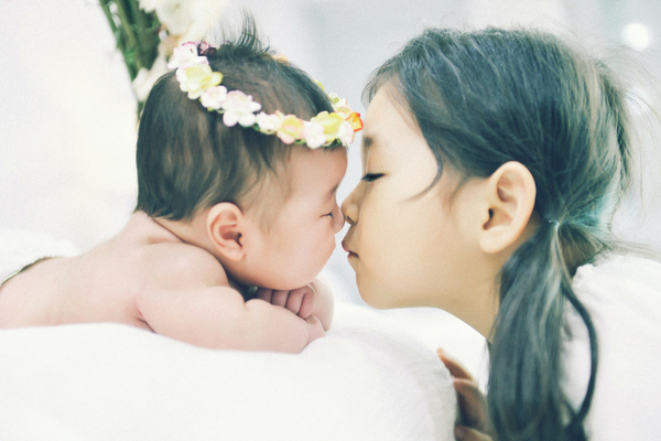Little girl kisses baby sibling | Sparkhouse Blog