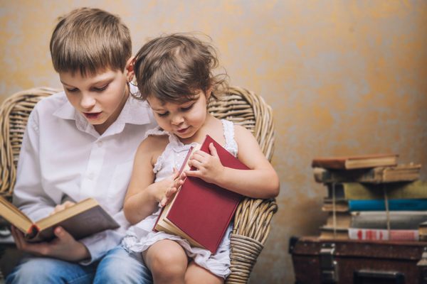 Older kid reads to younger kid | Sparkhouse Blog