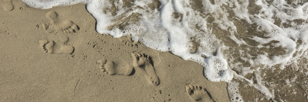 Footprints in the sand on a beach | Sparkhouse Blog