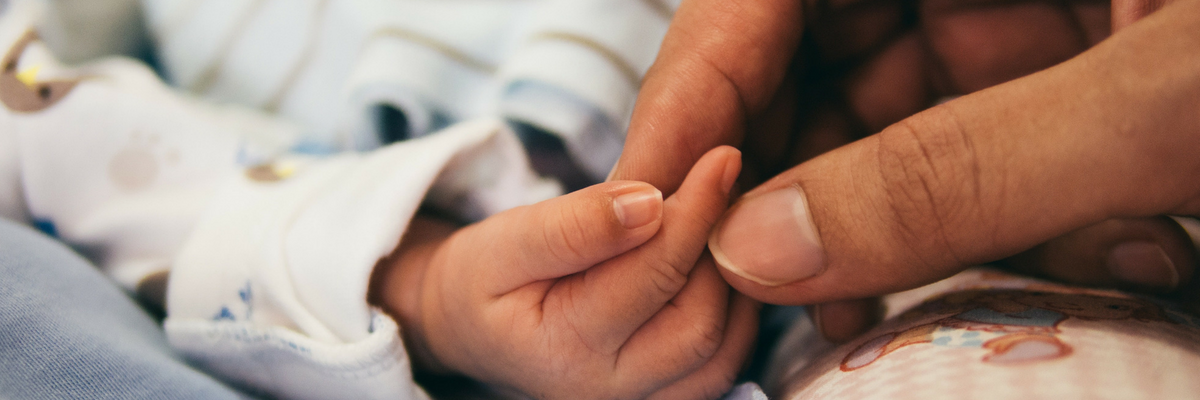 Adult holds hands with a baby | Sparkhouse Blog