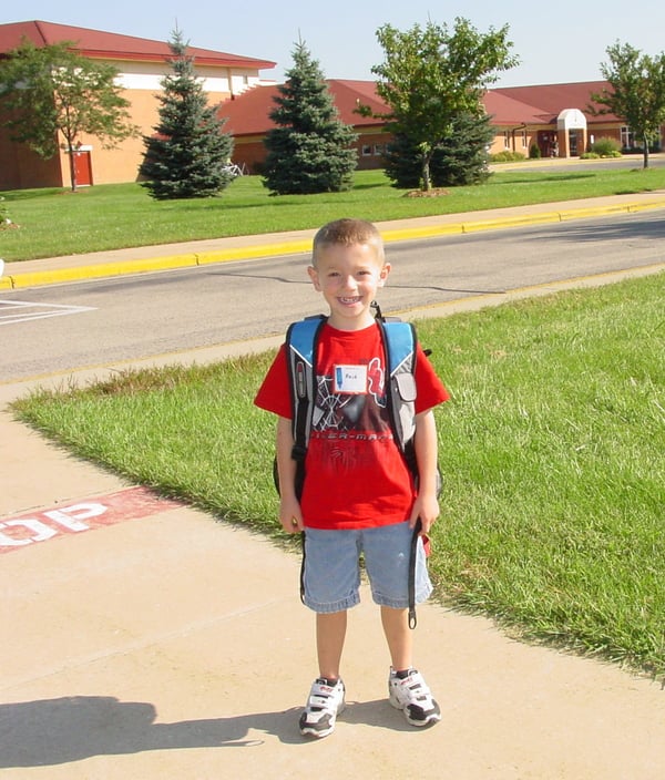 A kindergartener standing outside wearing a backpack